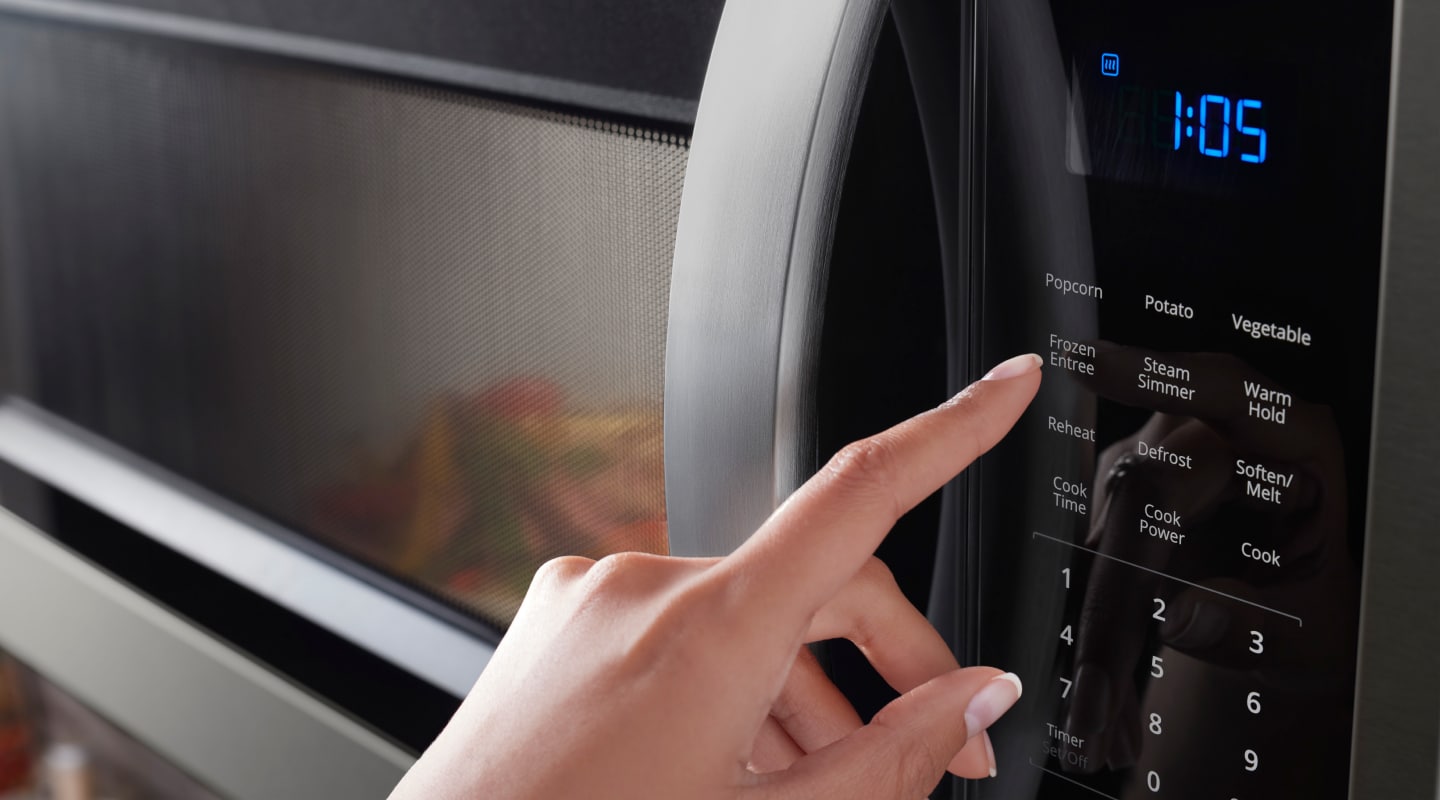 Person pressing button on a Whirlpool® microwave Person pressing button on a Whirlpool® microwave