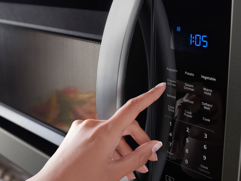 Person pressing button on a Whirlpool® microwave Person pressing button on a Whirlpool® microwave