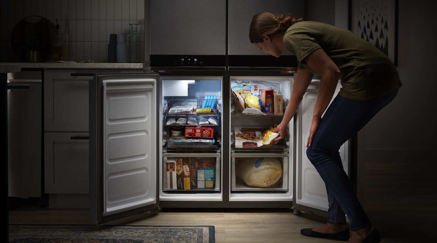 A person crouching before their Whirlpool® counter depth refrigerator