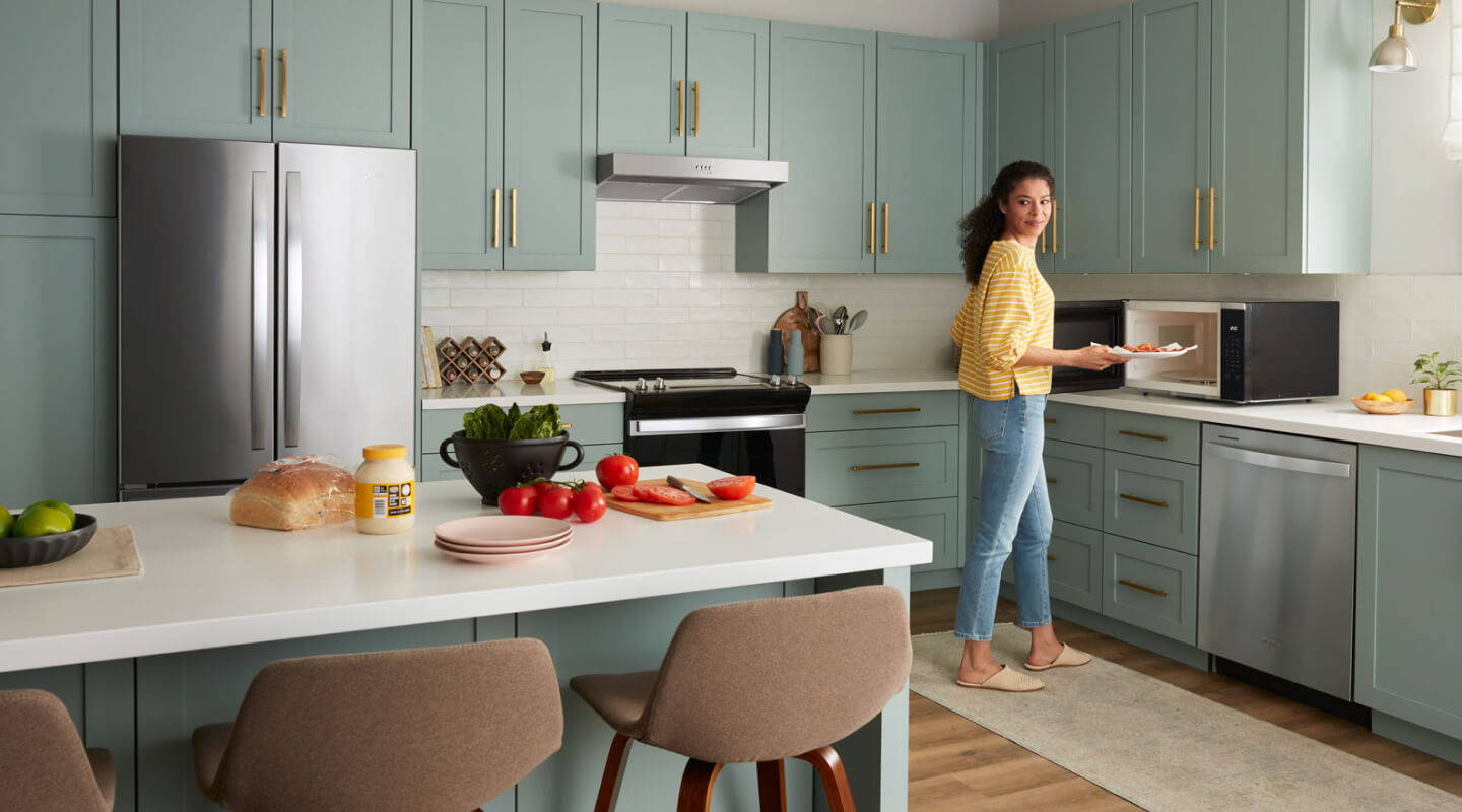 A person in a kitchen using a countertop microwave