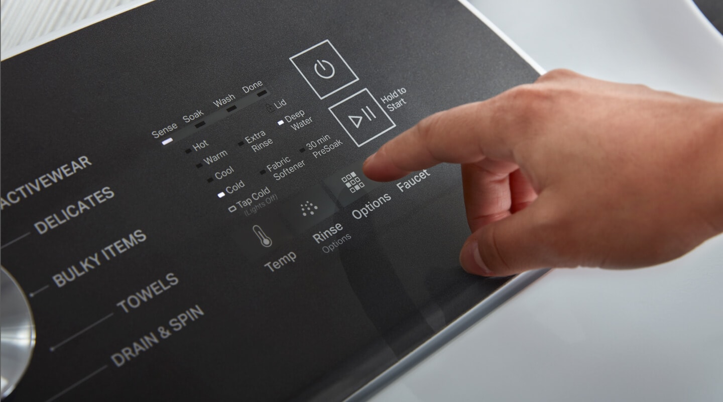 A hand selecting cycle settings on a washing machine control panel A hand selecting cycle settings on a washing machine control panel