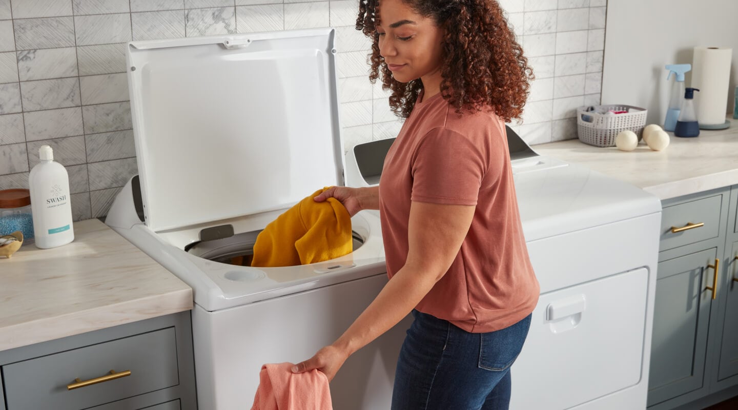 Person removing clothes from a top load washing machine Person removing clothes from a top load washing machine