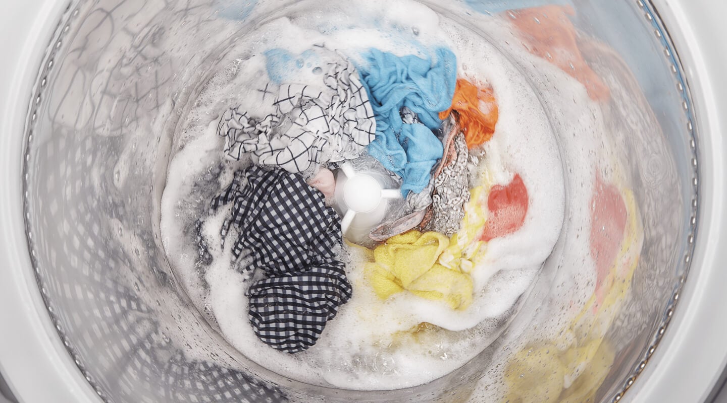 A load of clothes soaking inside a white washing machine A load of clothes soaking inside a white washing machine
