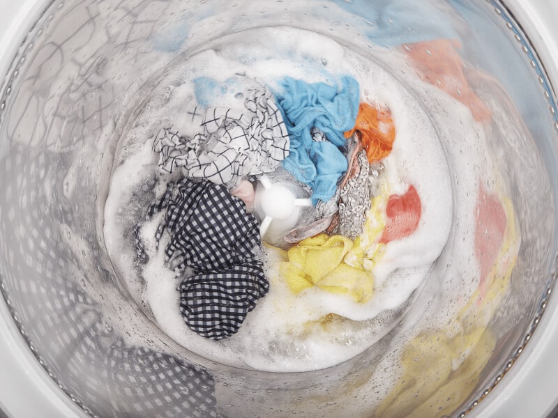 A load of clothes soaking inside a white washing machine A load of clothes soaking inside a white washing machine
