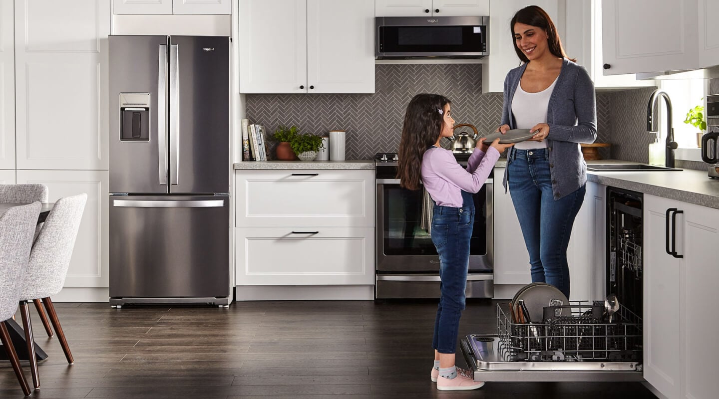 Person handing a child a clean dish next to a dishwasher Person handing a child a clean dish next to a dishwasher