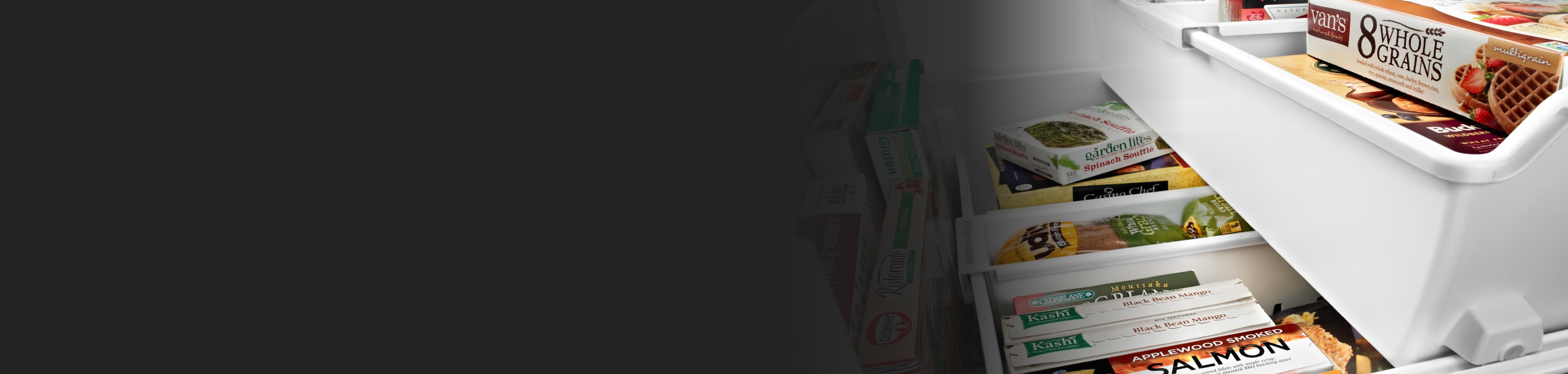 A variety of frozen groceries in the freezer compartment of a white refrigerator