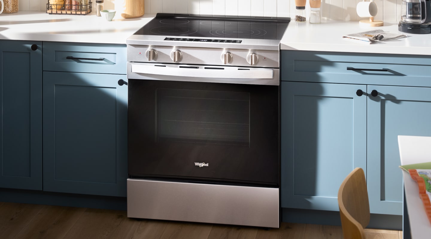 An electric slide-in range inside a kitchen with blue cabinets