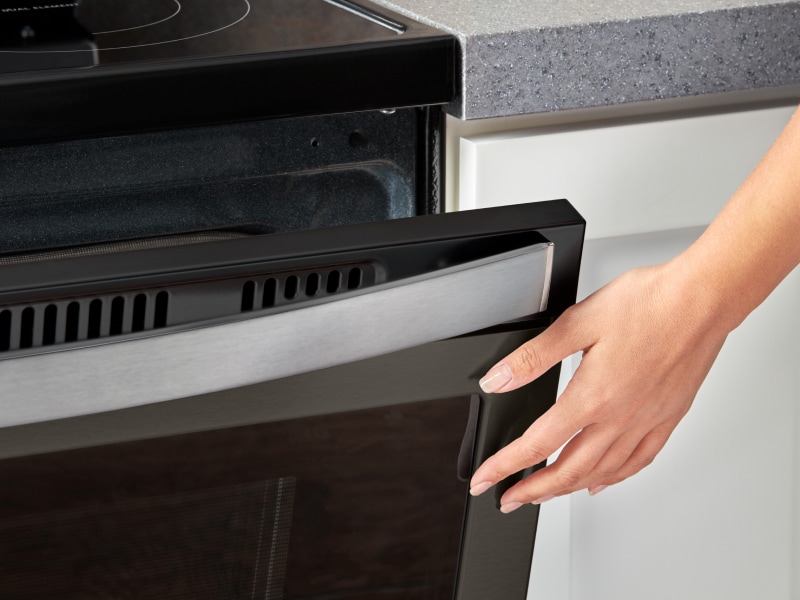 Person closing a slightly opened oven door Person closing a slightly opened oven door
