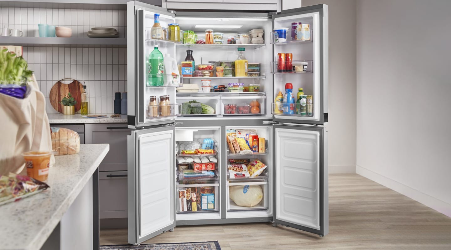 Open four door refrigerator full of groceries