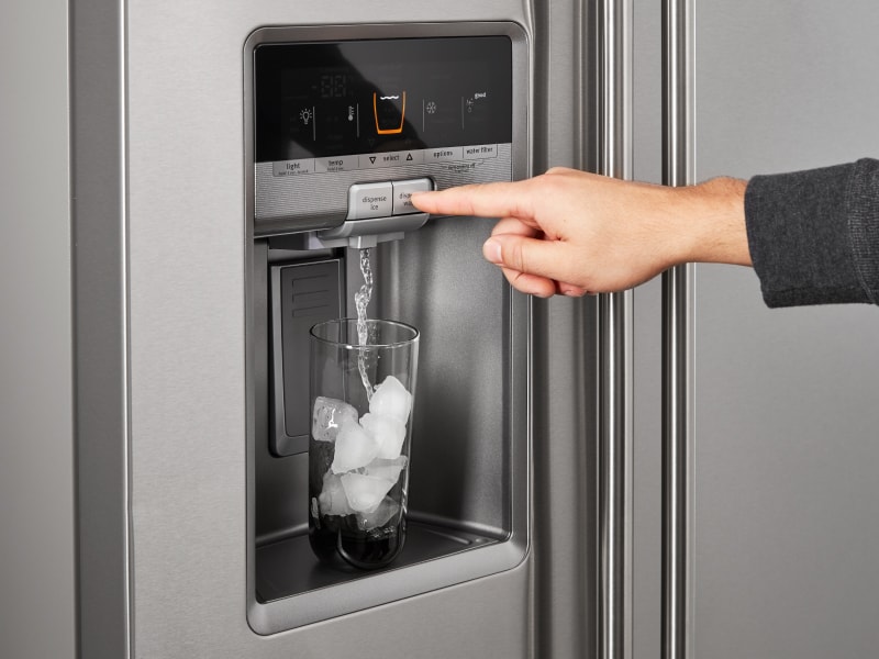 A person dispensing water out of a refrigerator ice maker A person dispensing water out of a refrigerator ice maker