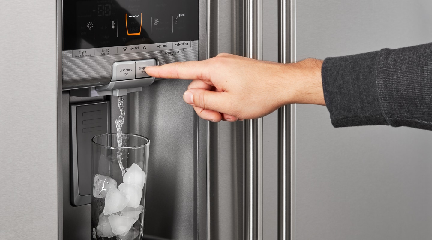 A person dispensing water out of a refrigerator ice maker A person dispensing water out of a refrigerator ice maker