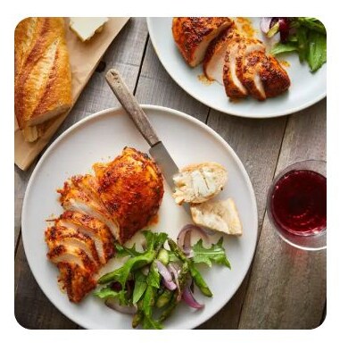 A plate of sliced, seasoned chicken breast with a side salad and bread A plate of sliced, seasoned chicken breast with a side salad and bread