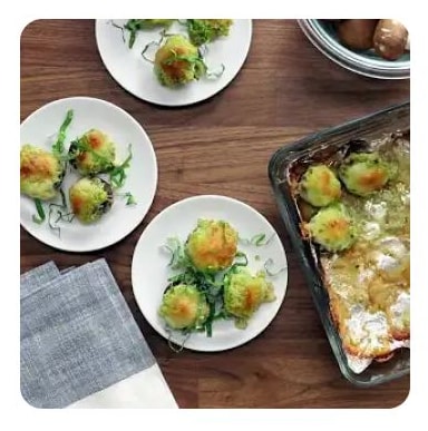 Three white plates with green pesto stuffed mushroom caps Three white plates with green pesto stuffed mushroom caps