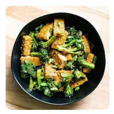 A black bowl with crispy, sautéed tofu and broccoli A black bowl with crispy, sautéed tofu and broccoli