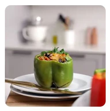 A stuffed green bell pepper on a white dish A stuffed green bell pepper on a white dish
