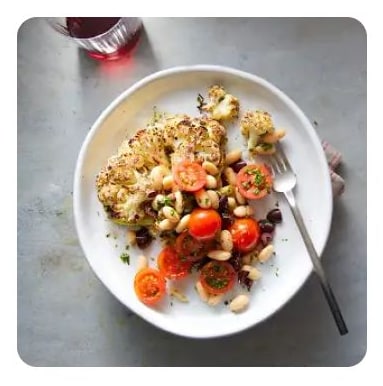 Charred cauliflower steak with cherry tomatoes on a plate Charred cauliflower steak with cherry tomatoes on a plate