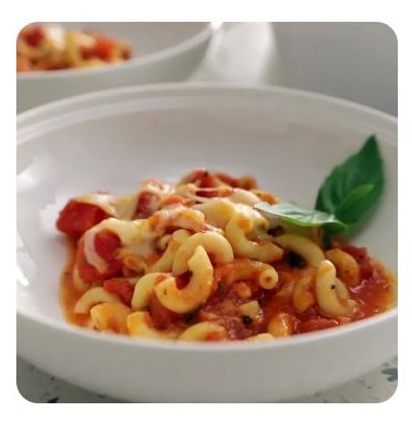 A white bowl filled with elbow noodles tossed in spaghetti sauce