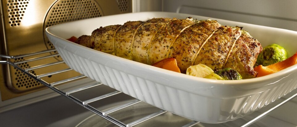 Roasted chicken and vegetables in a baking dish inside an oven Roasted chicken and vegetables in a baking dish inside an oven