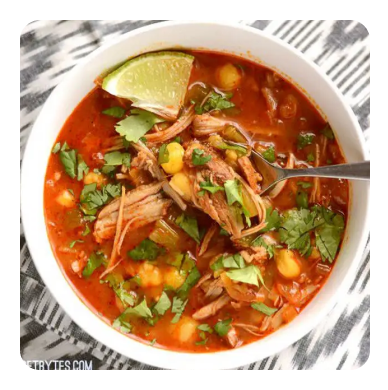 A bowl of tomato-based soup with shredded pork and herbs A bowl of tomato-based soup with shredded pork and herbs