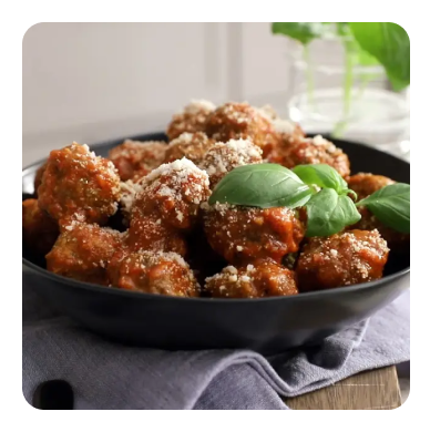 A bowl of meatballs in spaghetti sauce topped with basil A bowl of meatballs in spaghetti sauce topped with basil