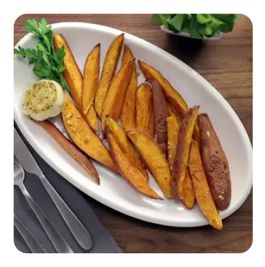 A white platter with sweet potato wedges and roasted garlic