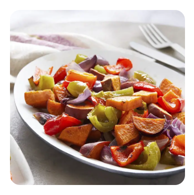 A serving dish with roasted bell peppers, sweet potatoes and onion