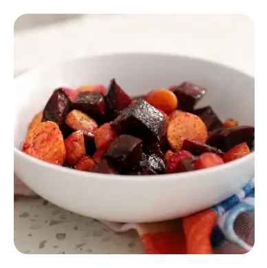 Chopped and roasted beets and carrots in a white bowl