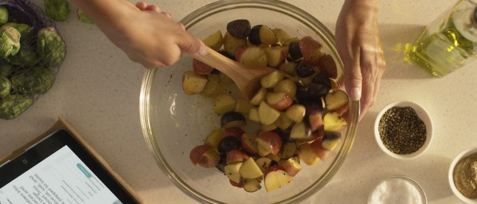 A person stirring seasoned potatoes in a bowl