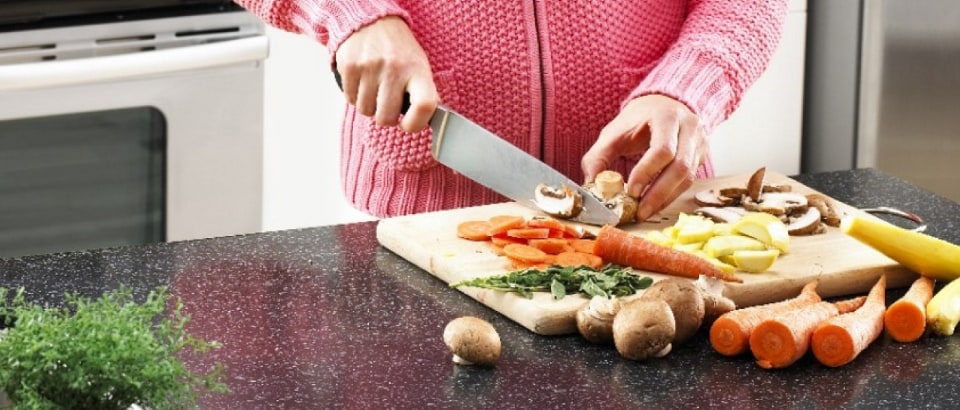 A person chopping vegetables on a wooden cutting board A person chopping vegetables on a wooden cutting board