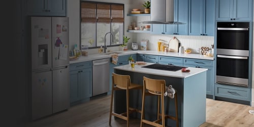 a beautiful kitchen in blue tones with stainless steel appliances and an island