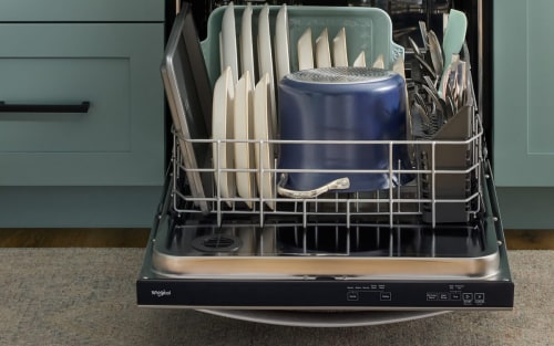 The bottom rack of a dishwasher that is fully loaded