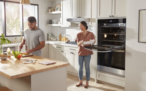 A woman pulling a pan out of her wall oven