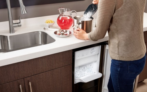 Someone shoveling ice into a container at a countertop