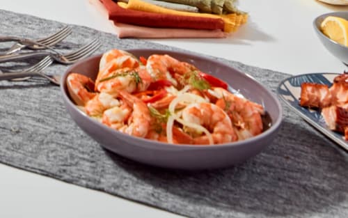 A bowl of shrimp pasta on a table with other fresh ingredients