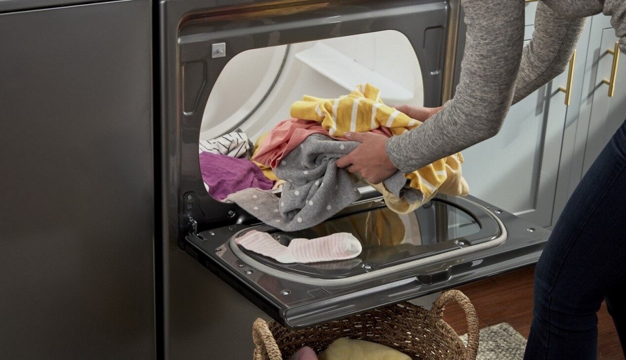 A person unloading clothes from a dryer A person unloading clothes from a dryer