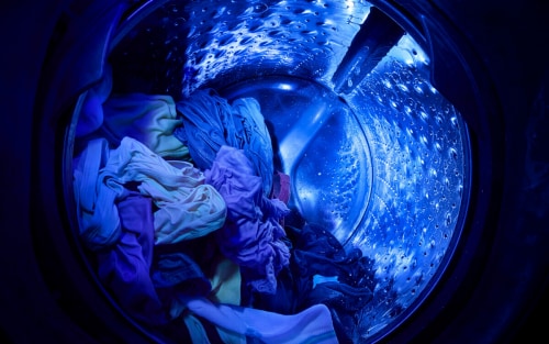 Blue UV light shining on clothes inside a wash basket with laundry