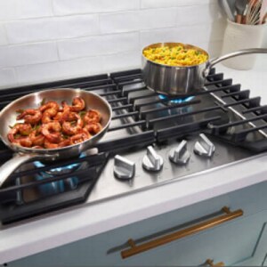 Shrimp and rice cooking in two pans on a gas cooktop