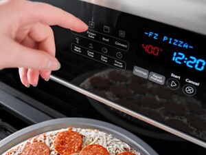 Hand about to select an oven setting on a gas stove control panel