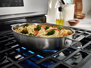 Oval braiser cookware with noodles and vegetables cooking on a gas stove