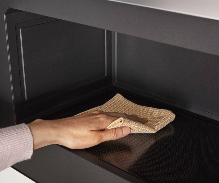 Quelqu'un essuie l'intérieur d'un four à micro-ondes encastré Whirlpool