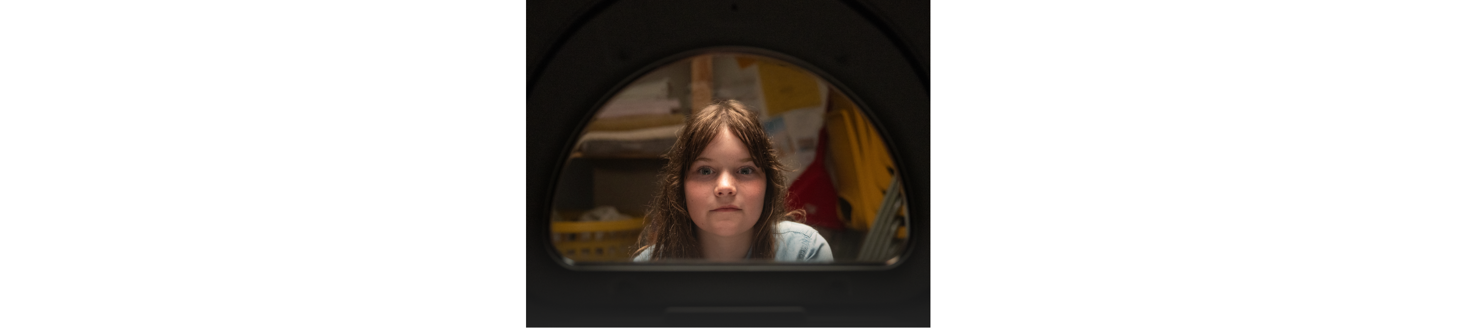A child’s face framed by a dryer opening