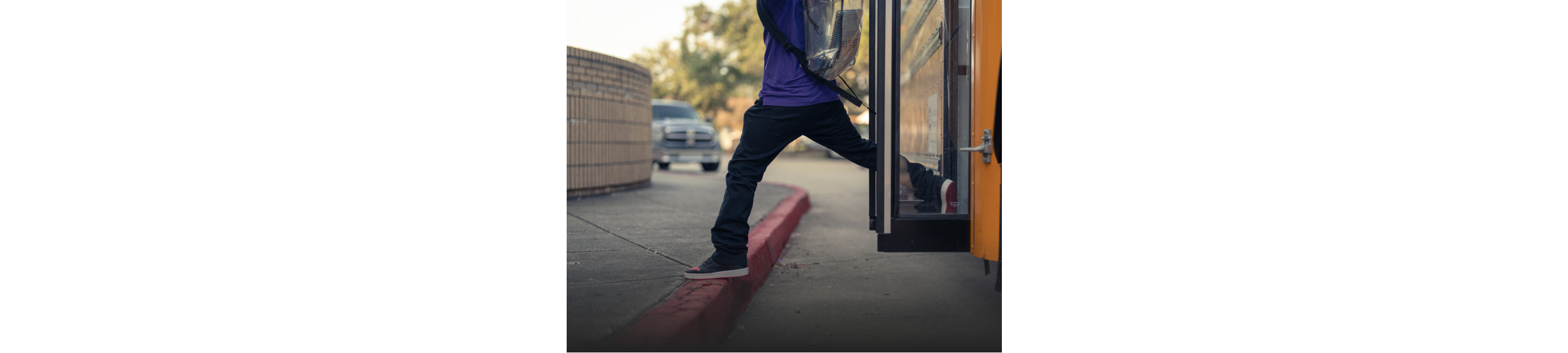 A child getting off a school bus onto the sidewalk curb