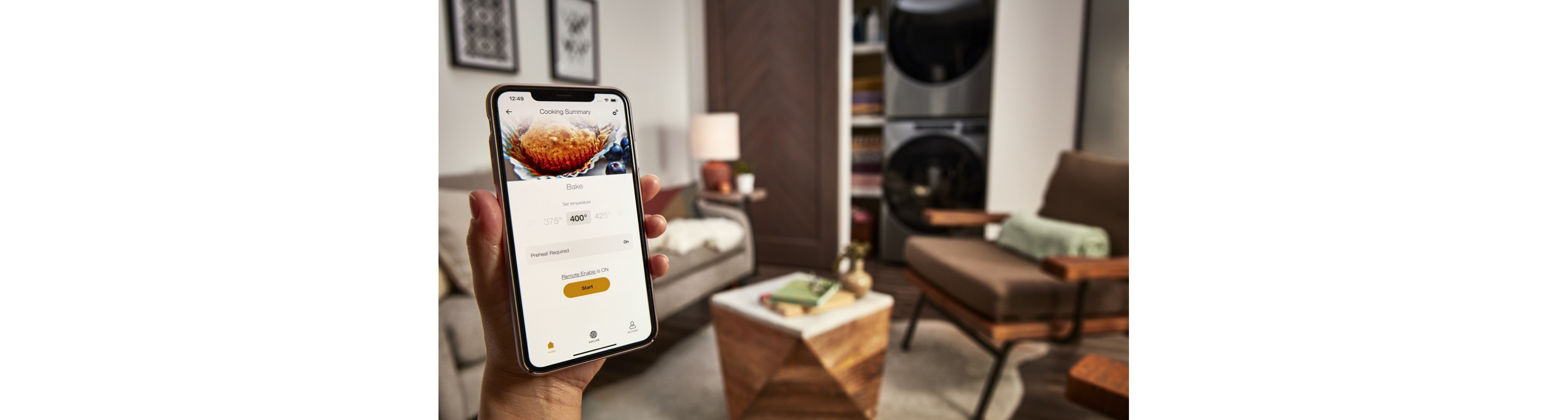 Closeup of a person holding a smartphone with the Whirlpool® App on the screen and a living area in the background 