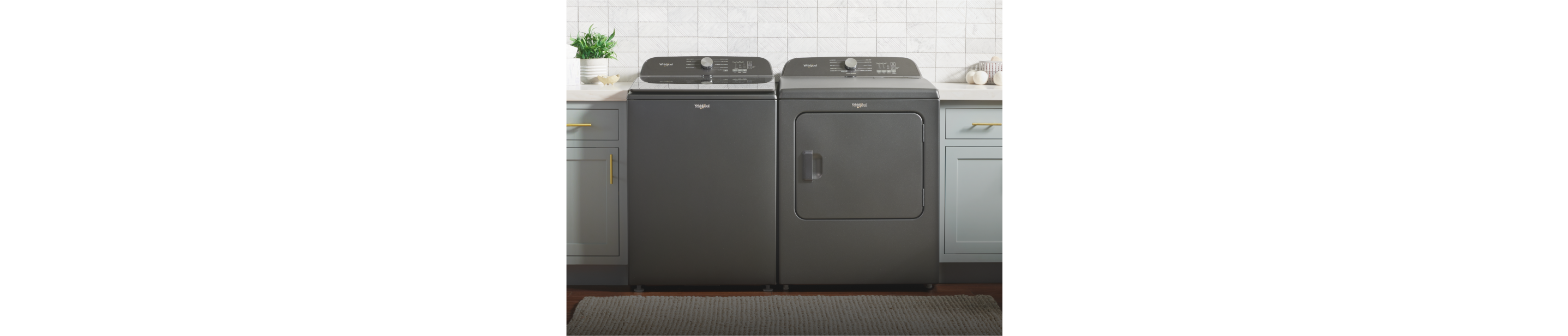 A dark gray Whirlpool® Top Load Washer and Dryer in a laundry room