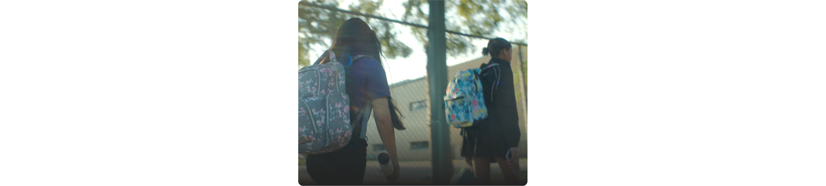 Kids with backpacks walk outside a school