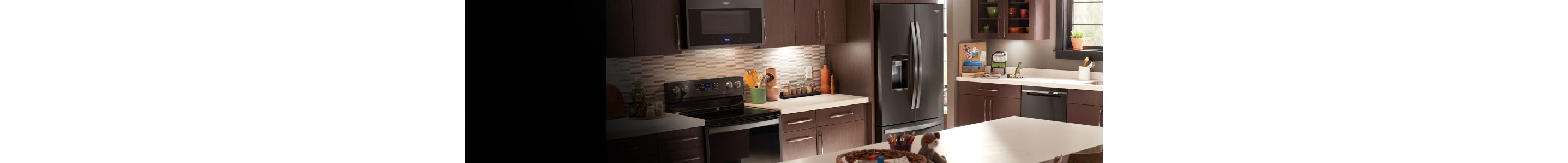 A sleek kitchen featuring a Whirlpool® black stainless steel refrigerator.