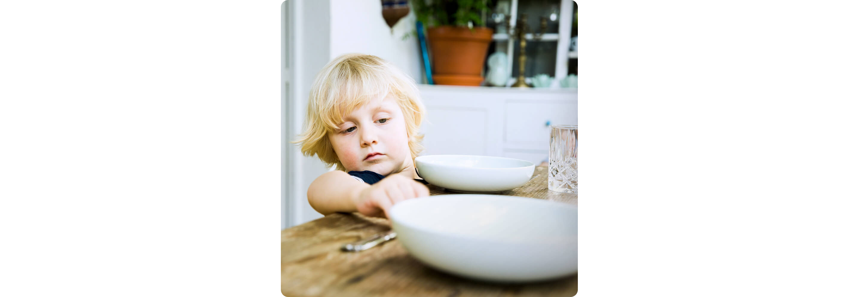 A young child setting the table with plates, silverware and glasses