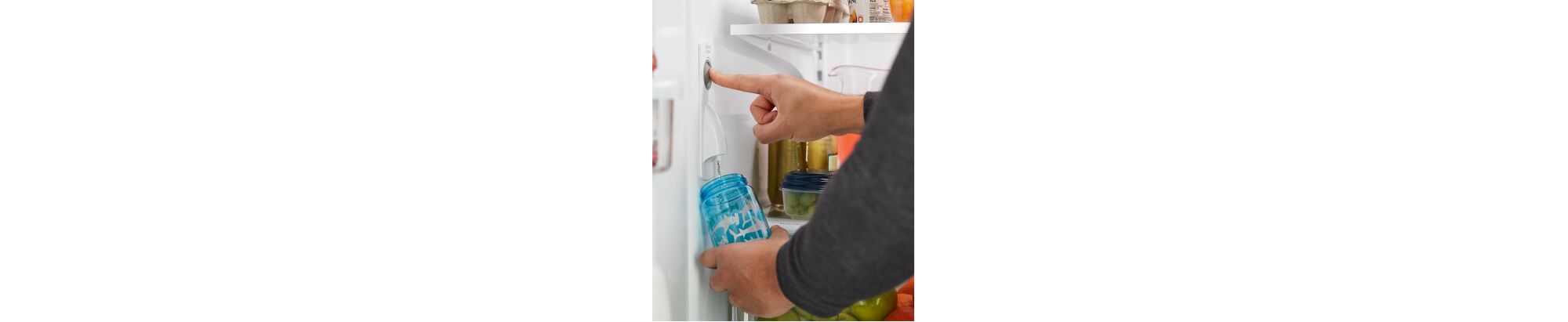 À l'intérieur d'un réfrigérateur bien approvisionné, une personne remplit une bouteille d'eau réutilisable à partir du filtre à eau interne du réfrigérateur