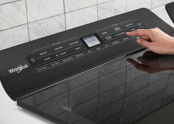 Someone pressing a button on the control panel of a Whirlpool Laundry Appliance