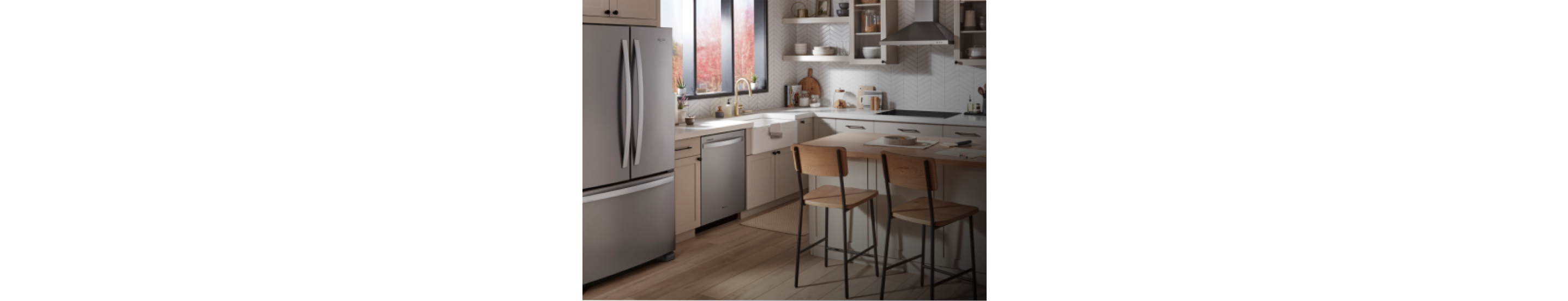A kitchen with light cabinets and an island with two counter-height chairs
